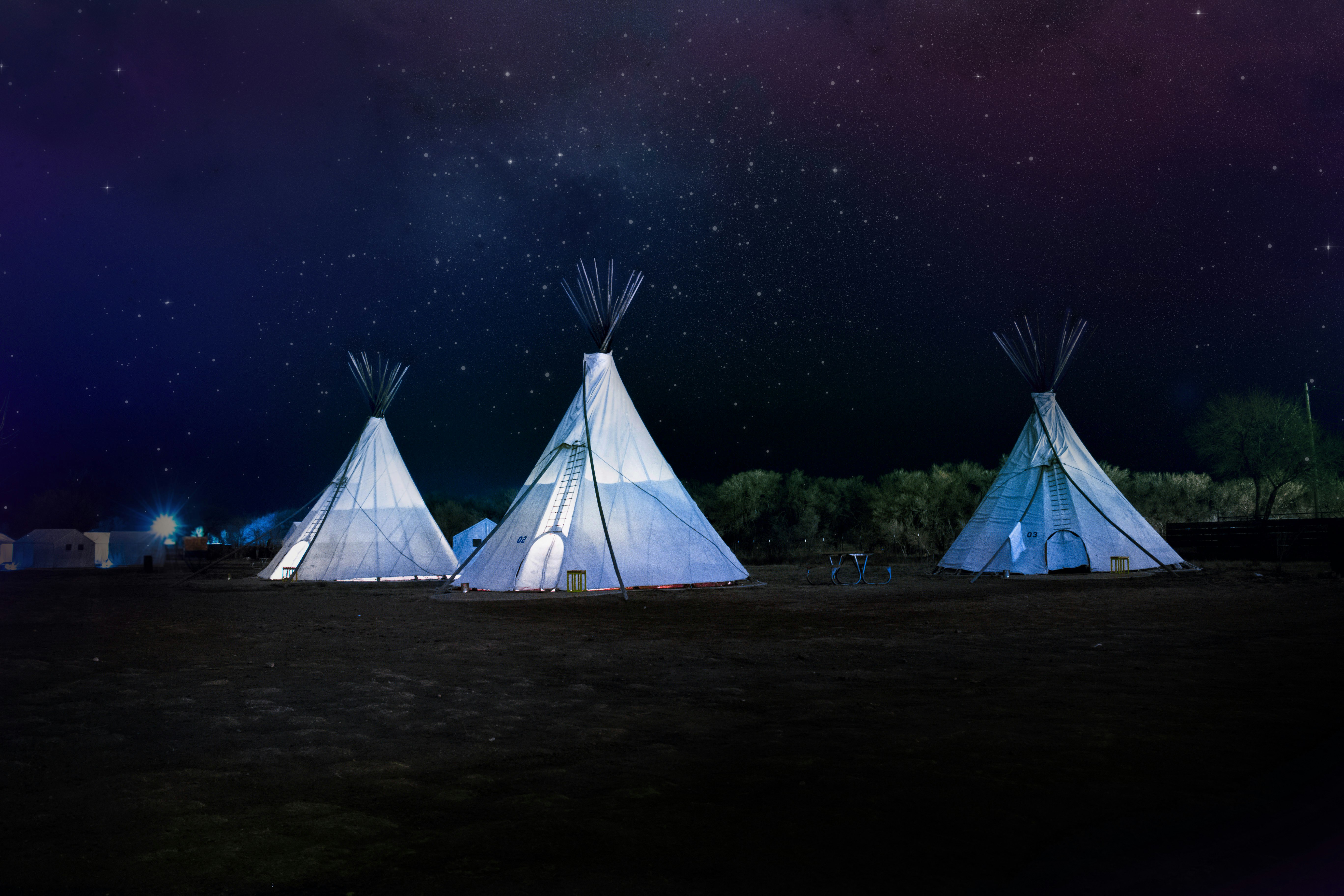 three white teepee tents under starry sky